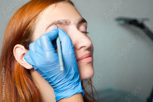 Canvastavla The master on the eyebrows draws the shape of the grafted eyebrow shape in a blu