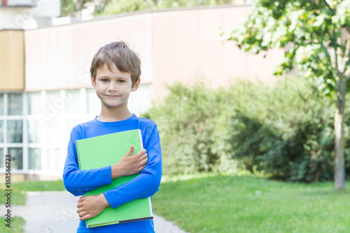Little boy holding book outdoors