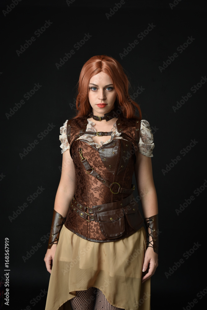 portrait of a red haired girl wearing steampunk costume. black studio background. portrait of a red haired girl wearing steampunk costume. black studio background.