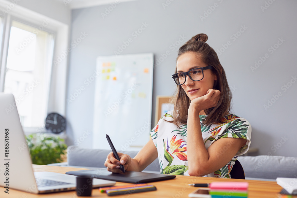 Pretty young graphic designer working in her home office Pretty young graphic designer working in her home office