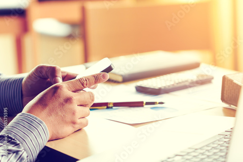 Canvas Print Businessman hang holding smartphone and searching data result of finance at office room