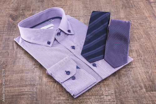 Man's shirt folded and two ties on a wooden background