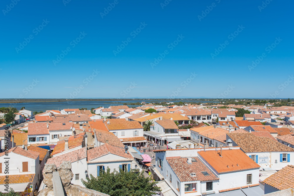      Saintes-Maries-de-la-Mer in Camargue, panorama of the town, tiles roofs, and the swamps, view from the church 
