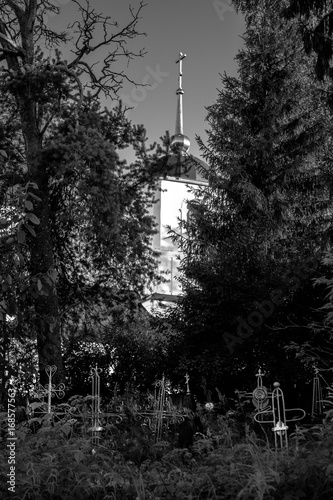 Old cemetery landscape. Church in a dark forest, grave crosses in the foreground.