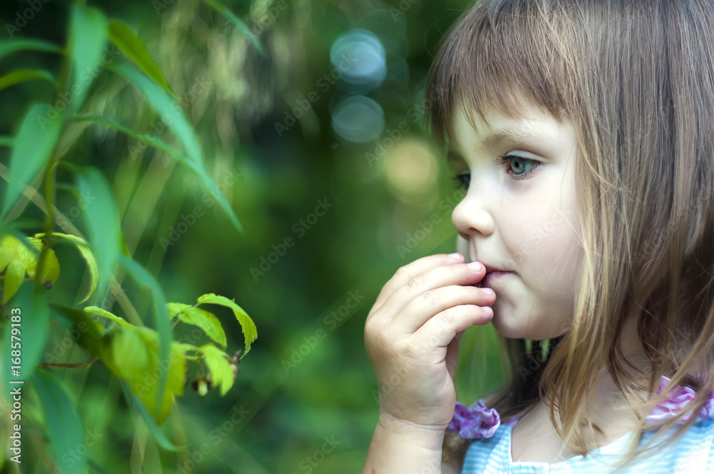 Adorable little girl in white dress in the forest eating berries. Forest Nymph. Sunny day