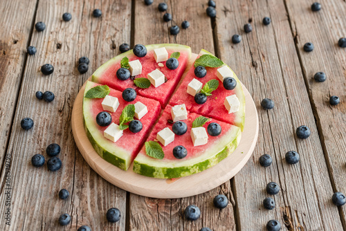 Sliced, juicy watermelon pizza with blueberries and cheese