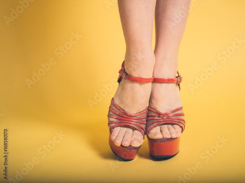 Woman in red stripper heels on yellow photo