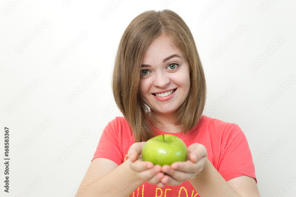 Portrait photo of smiling pretty girl with bob hairstyle holding green apple in both hands as if suggesting it, healthy lifestyle or fruit diet. White background Portrait photo of smiling pretty girl with bob hairstyle holding green apple in both hands as if suggesting it, healthy lifestyle or fruit diet. White background