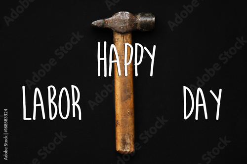 happy labor day text sign. hammer, tool for repairing and renovation concept on black background top view. working instruments for repairing and fixing, flat lay, copy space. minimalistic image