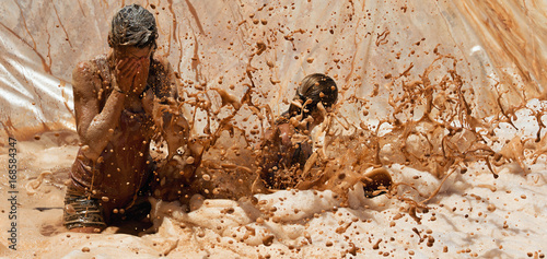 Mud race runners, jump into dirty water with foam photo