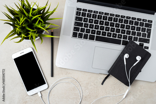 Modern laptop with smart phone and accessories on gray stone table