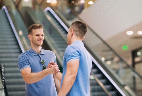 Smiling friends shaking hands in a shopping mall
