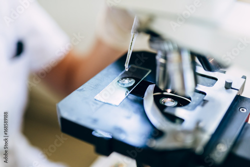 Unrecognizable worker or scientist working with microscope in laboratory