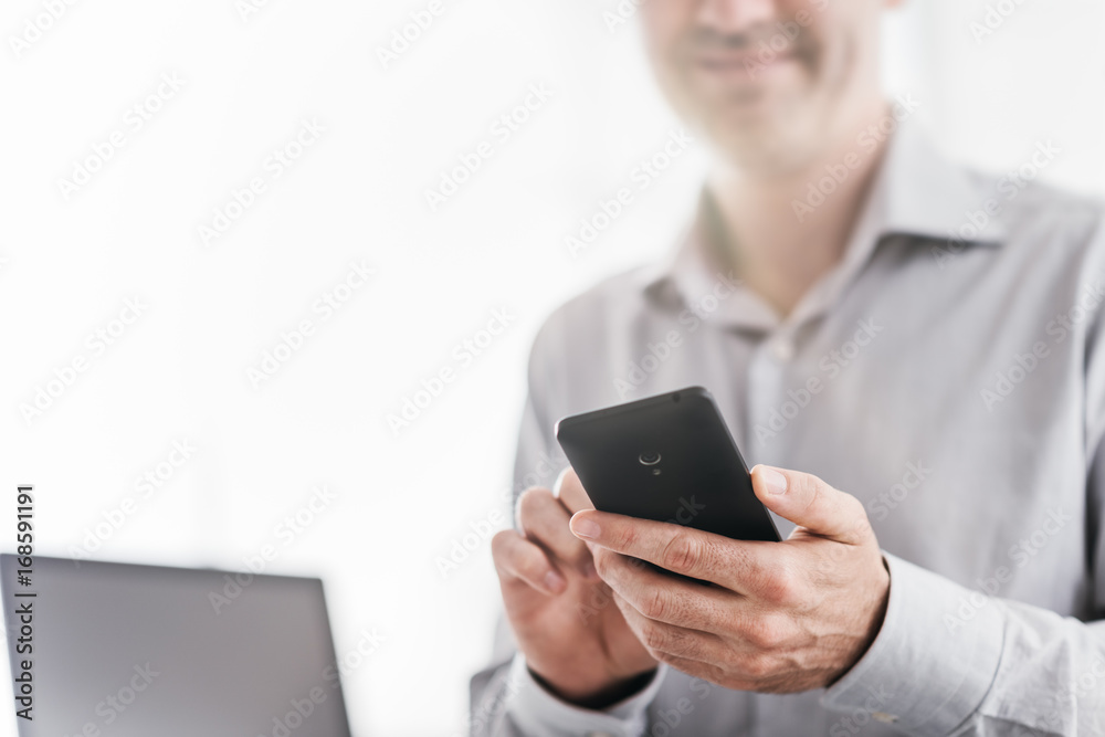 Businessman using a smartphone in his office Businessman using a smartphone in his office