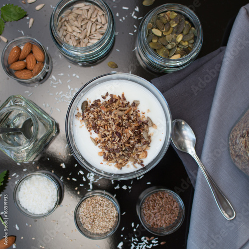 Granola on yogurt surrounded with its ingredients 