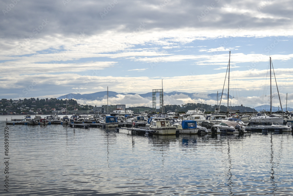 View of the marina in the town of Leirvik, Norway, in the background overcast sky over the fjords.