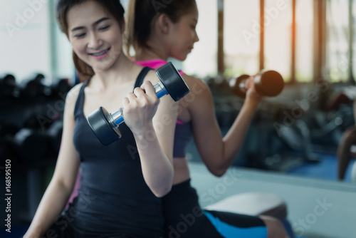 Beautiful girl exercising by lifting a dumbbell for health care in a public gym. Health care concept