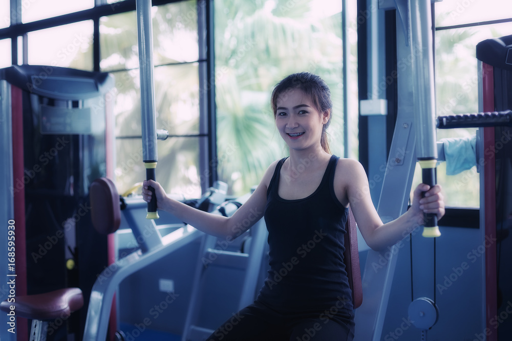 Beautiful girl exercises by pulling the rope to strengthen the muscles in the public gym. Strength training of the arm muscles. Health care concept Beautiful girl exercises by pulling the rope to strengthen the muscles in the public gym. Strength training of the arm muscles. Health care concept