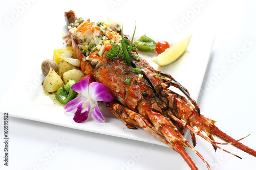 Stir-fried Lobster with Garlic & Butter Sauce on white square porcelain plate Isolated on white background with shadow Over Front view, Expensive Seafood. Selective Focus at Head of Lobster