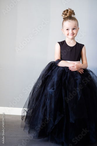 5 year old girl in a black dress on a gray