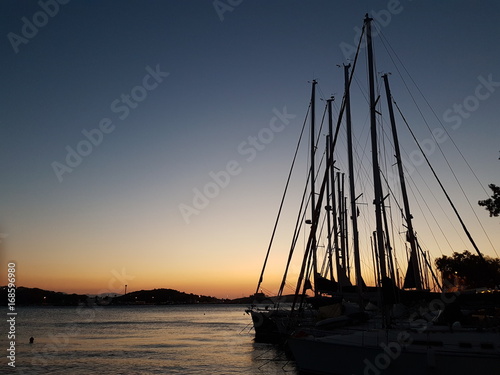 silhouettes of sail poles at sun set