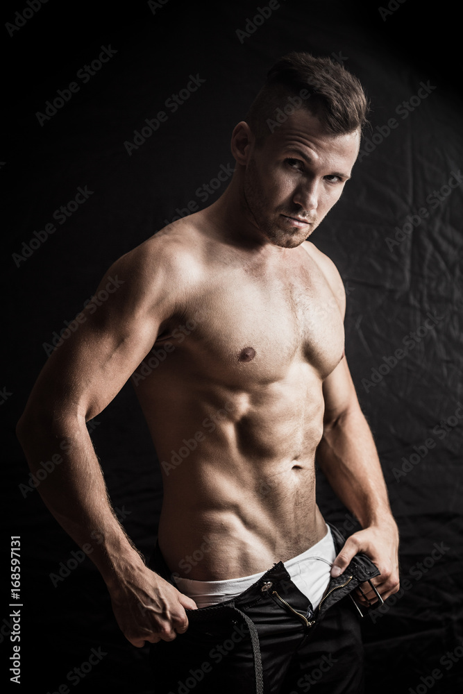 man sexually removes clothes on a dark background man sexually removes clothes on a dark background