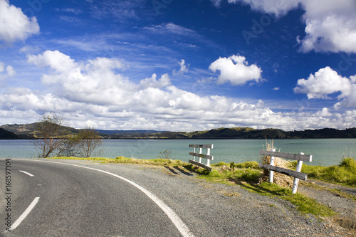 Road along a lake with white clouds above it