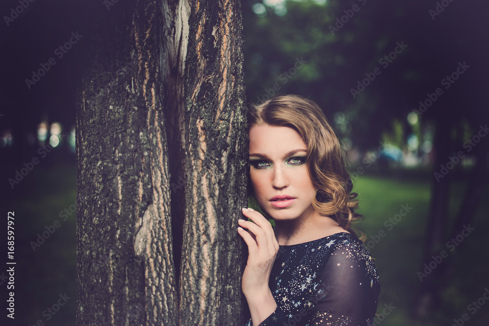 Portrait of relaxed young lady in a summer park waiting. Beautiful young girl with blonde curly hair , outdoor. Portrait of relaxed young lady in a summer park waiting. Beautiful young girl with blonde curly hair , outdoor.