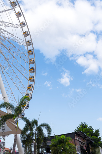 Large Ferris wheel, with blue skies and clouds background.