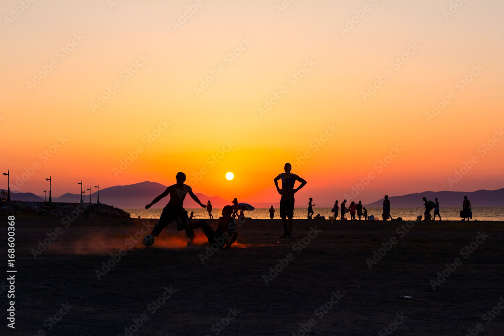 Silhouetted shot of young people are having fun on beach and playing football Silhouetted shot of young people are having fun on beach and playing football