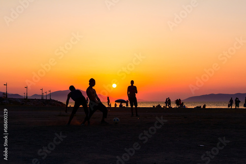 Silhouetted shot of young people are having fun on beach and playing football © Roman_23203