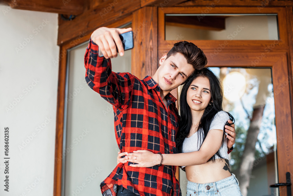 Happy romantic couple taking a photo with smart phone. Beautiful young girl  and man hug and laugh taking a selfie. Urban fashion style Photos | Adobe  Stock