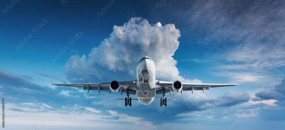 Naklejka premium Piękny samolot. Krajobraz z białym pasażerskim samolotem lata w niebieskim niebie z chmurami przy chmurzącym dniem. Tło podróży. Samolot pasażerski. Podróż służbowa. Samolot komercyjny. Samolot