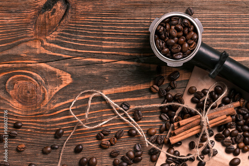 Coffee beans and cinnamon sticks on rustic wooden table, view fr