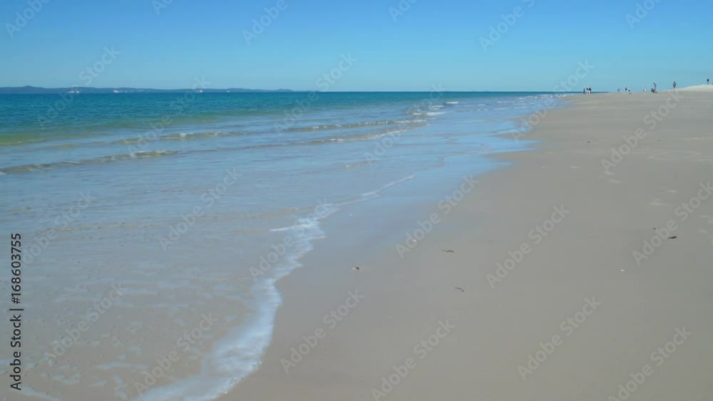 Wide shot of quiet beach with waves rolling in on a sunny day. Wide shot of quiet beach with waves rolling in on a sunny day.