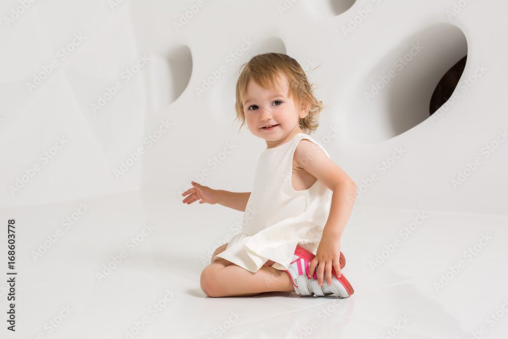Smiling little girl sitting on the floor on a white background Stock ...