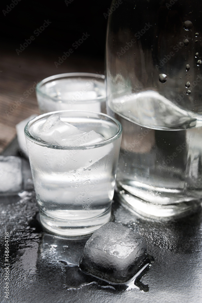 Close-up view of bottle vodka with glasses standing on ice black
