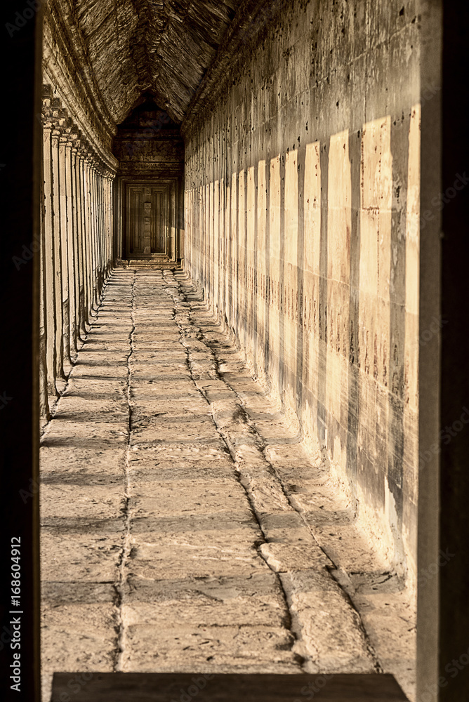 Stone corridor in Angkor Wat temple with sun rays in Cambodia
