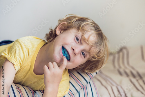 Three-year old boy shows myofunctional trainer to illuminate mouth breathing habit. Helps equalize the growing teeth and correct bite. Corrects the position of the tongue photo