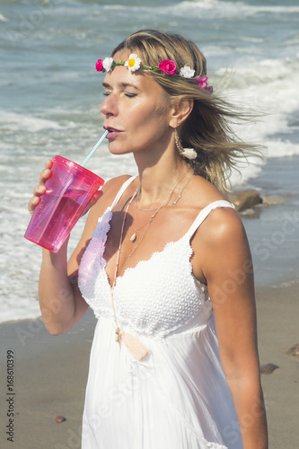 woman in white dress by the ocean and drinking