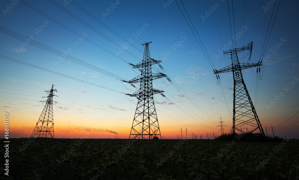 Silhouette of electricity pylons and high-voltage power lines on the field at sunset. Wire electrical energy at sunrise