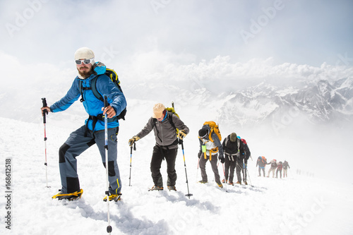 A group of mountaineers climbs to the top of a snow-capped mountain