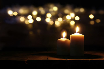 Burning candles over old wooden table with bokeh lights