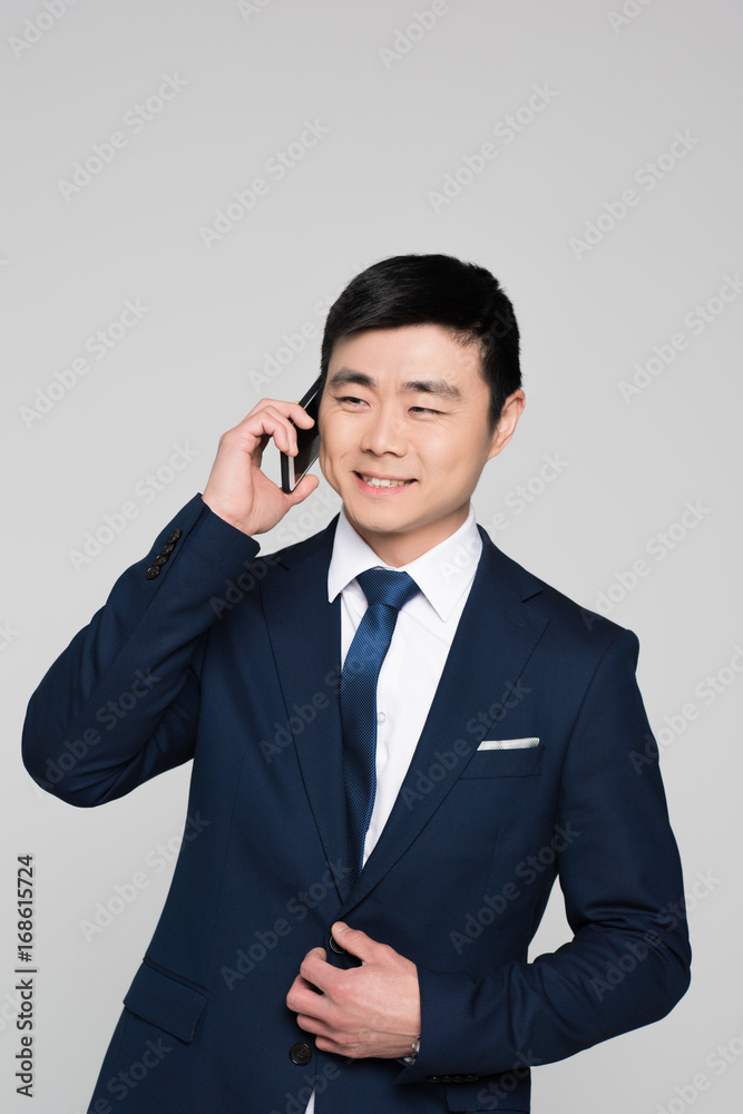 Half-length shot of smiling businessman in a suit talking on the phone Half-length shot of smiling businessman in a suit talking on the phone