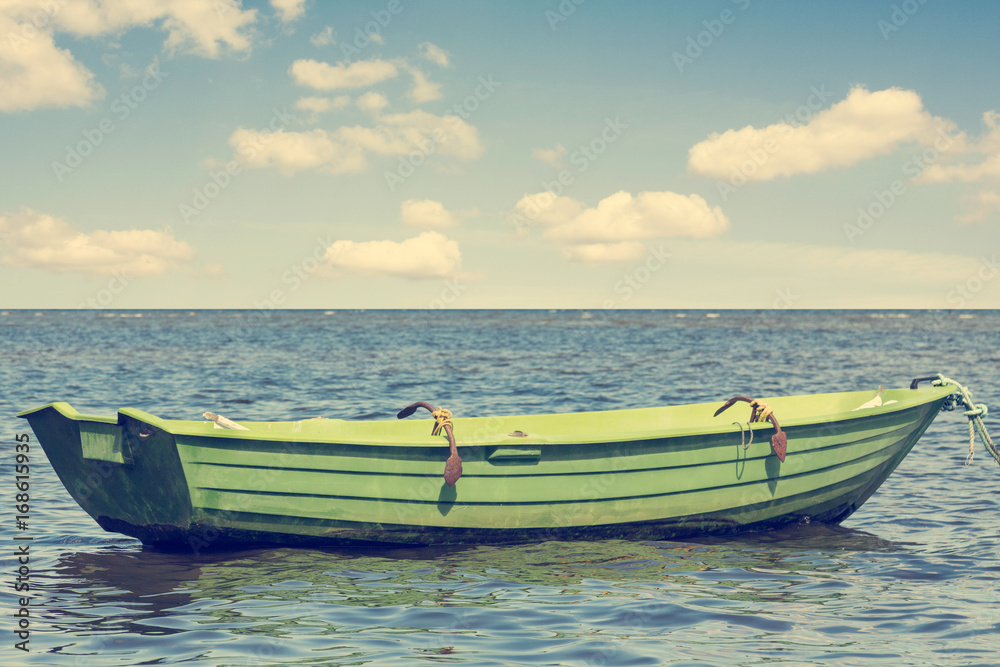Green wooden boat floating out to sea
