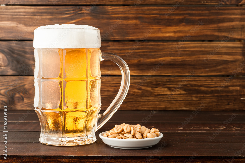glass of cold frothy lager beer and snacks on wooden table glass of cold frothy lager beer and snacks on wooden table