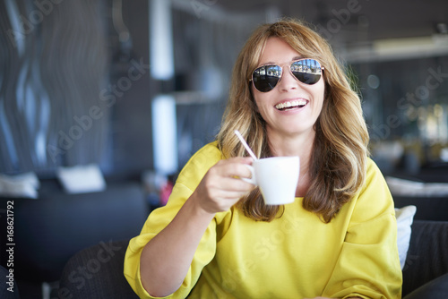 Middle aged woman portrait in cafe. Close-up portrait of a laughing middle aged woman sitting at cafe and drinking morning coffee.