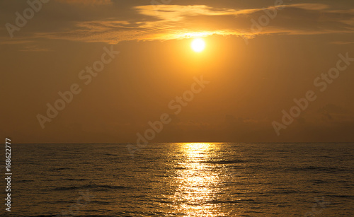 Bright orange sunset over the sea leaving in the distance on the surface of the water