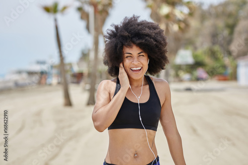 Happy afro american girl listening music on beach