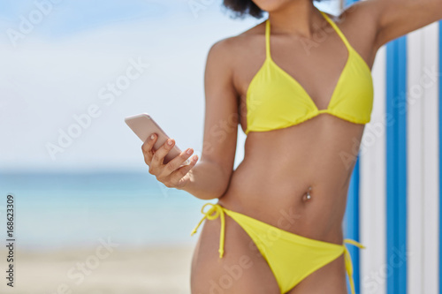 Young woman in bikini holding smartphone